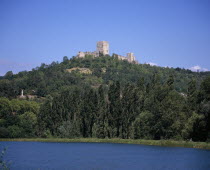 Chateau Puivert  view from south high on wooded hillside above village and its lake.  Cathar castle stronghold during war with the Catholic church in the 13th century.