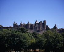 Carcassonne.  City view from west towards medieval fortified outer walls of old town and the chateau of the Count of Carcassonne with trees in the foreground.