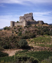 Chateau de Aguilar.  Ruins of twelth Century Cathar castle set on hillside in the commune of Tuchan.  Inner keep surrounded by outer thirteenth century fortification.Vines growing in valley below.