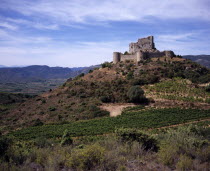 Chateau de Aguilar.  Ruins of twelth Century Cathar castle set on hillside in the commune of Tuchan.  Inner keep surrounded by outer thirteenth century fortification.Vines growing in valley below.