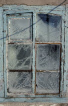 Detail of window with pale blue painted frame and frost patterns decorating the panes.