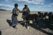 Ceremony of libation of first mare s milk of the season for crop of foals.  Herdsmen pour milk on to head of foal.