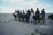 Young herdsmen circling camp abreast on horseback for ceremony of libation of first mare s milk of the season.