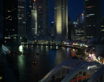 Singapore river basin at night with city skyscraper lights reflected in the water and light trails from traffic crossing bridge in the foreground.