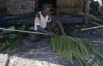 Malaita Province  Lau Lagoon  Foueda Island.  Traditional building methods  man stitching lengths of palm leaves to narrow strip of wood to use in house construction.