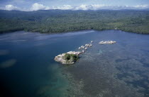 Malaita Province  Lau Lagoon  Foueda Island.  Aerial view over artificial man made island and houses with mainland covered by dense forest beyond.