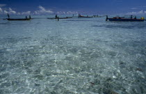 Malaita Province  Lau Lagoon. Distant fishing team and boats.  Expanse of turquoise sea with light reflections in foreground and blue sky.