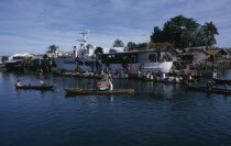 Malaita Province  Lau Lagoon. Weekly boat service visiting Foueda Island attracting crowds in canoes.  Thatched housing behind.