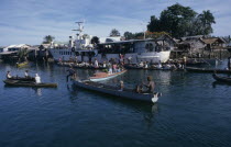 Malaita Province  Lau Lagoon. Weekly boat service visiting Foueda Island attracting crowds in canoes.  Thatched housing behind.