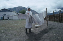 Nurse in white uniform hanging out hospital linen.