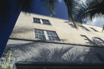 South Beach. Detail of Art Deco building. Angled view with palm trees creating shadows on exterior.