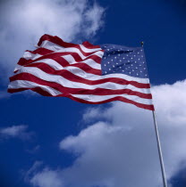 American Stars and Stripes National Flag blowing in the wind against a blue sky with clouds
