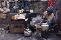 Tea-wallah preparing tea boiled with milk and sugar and served in glasses to sell in market.