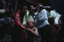 Buddhist priests and family bless young boy with milk during his bhartavan or manhood ceremony.