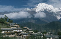 Gurung village on steep  terraced slope with Annapurna South in the background.  The Gurung are indigenous peoples and devout Buddhists.