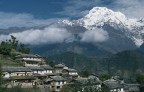 Gurung village on steep  terraced slope with Annapurna South in the background.  The Gurung are indigenous peoples and devout Buddhists.