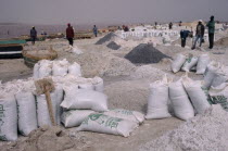 Bags of salt on salt flats with workers behind.