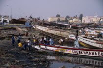 Children playing on shore next to beached boats.