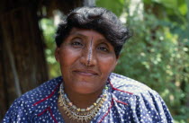Portrait of an older Kuna woman  the wife of the island chieftain  wearing a monkey tooth necklace with a black line drawn along length of nose. Cuna