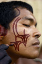 Barasana man  sub group of Tukano  decorating his face with red ochote facial paint for manioc festival and dance ceremonial. Hands wrists and body decoration with dark purple/black juice from We leav...