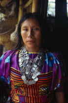 Three-quarter portrait of Kuna Indian woman from the Arquia community wearing traditional Mola applique layered design of mythical Kuna birds  gold nose ring with black line drawn along length of nose...