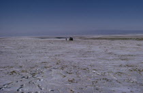 Mid-winter on the edge of the Gobi with a distant Russian Gaz jeep and lone figure walking in barren frozen landscape