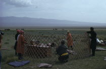 Khalkha herdsmans family erecting ger or yurt on summer grassland pasture for sheep grazing. First the wooden frame is erected. Khalha East Asia Asian Mongol Uls Mongolian Scenic