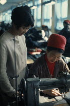 Woman working at sewing machine in Ulan Bator tannery  leather factory with a young supervisor overseeing her work.East Asia Asian Female Women Girl Lady Mongol Uls Mongolian
