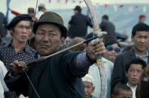 Nadam  National Day celebrations  archery competition in Ulan Bator stadium  competitor flexes Mongolian longbow to fire at target