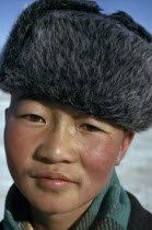 Altai provincial capital. Portrait of young boy with typical fur hat with ear flaps against bitter winter cold.