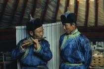 Flute player and chanter in fine traditional silk tunics during celebrations for the Mongolian Lunar New Year or Tsagaan Tsaar. East Asia Asian Classic Classical Historical Mongol Uls Older