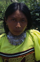 Head and shoulders portrait of Kuna woman from the Arquia community wearing gold nose ring  necklace of old Colombian and Panamian coins and traditional mola design applique panel and facial decoratio...