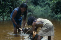 Makuna mother and daughter washing manioc roots brought in from chagra cultivation plot  prior to rubbing down on flint inlain board to make farinha flour and casabe. Tukano Makuna rio Piraparana Vaup...