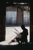 Makuna head man Ignacio making cane basket silhouetted in entrance to maloca or communal home.Tukano  Makuna Indian North Western Amazonia moloka American Colombian Columbia Hispanic Indegent Latin Am...