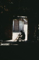 Makuna head man Ignacio making cane basket silhouetted at entrance to maloca or communal home.Tukano  Makuna Indian North Western Amazonia moloka American Colombian Columbia Hispanic Indegent Latin A...