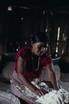 Makuna maloca/communal tribal home  interior with woman rubbing down manioc roots on a flint inlain board  to make flour for casabe. Tukano Makuna Indian North Western Amazonia maloca cassava American...