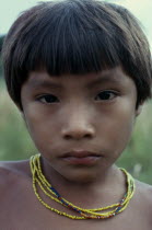 Head and shoulders portrait of young Barasana boy looking direct to camera  wearing multi-strand coloured bead necklace.Tukano sedentary Indian tribe North Western Amazonia