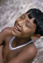 Head and shoulders portrait of laughing Barasana boy wearing multi-strand white glass bead necklace.Tukano sedentary Indian tribe North Western Amazonia American Colombian Columbia Hispanic Indegent K...