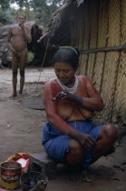 Barasana woman Paulina  applying red ochote fruit body paint to arms and upper body in preparation for manioc festival.  Hands already coloured dark purple to wrists with we dye from boiled leaves. T...