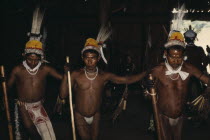 Barasana manioc festival.  Line of male dancers wearing full ceremonial regalia   royal crane macaw and toucan feather head-dresses   bodies and faces painted with dark purple "we" leaf juice and red...