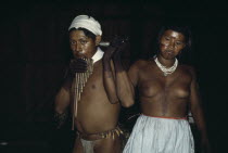 Group of young Barasana dancing a panpipe dance inside maloca/communal home - their bodies and faces painted with red ochote for ceremonial manioc festival.Tukano sedentary Indian tribe North Western...