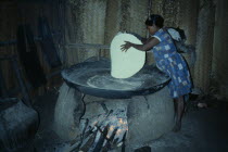 Barasana woman making casabe bread from manioc flour baked on large circular shallow clay oven over wood fire enclosed by clay oven wall. Tukano sedentary Indian tribe North Western Amazonia cassava...