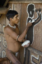 Cropped shot of Barasana Indian painting spirit guardian on front of maloca  communal home.Tukano sedentary tribe Indian North Western Amazonia maloca American Colombian Columbia Hispanic Indegent La...