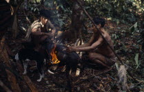 Maku hunters with dog  singeing hair from carcass of wild boar over open fire.indigenous tribe indian nomadic American Colombian Columbia Hispanic Indegent Latin America Latino South America Vaupes V...