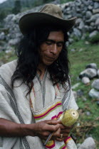 Ika man in traditional dress with hand woven mochila shoulder bag and holding poporo a small gourd containing finely powdered lime from burnt sea shells.He sticks the the lime into a wad of coca leave...
