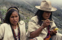 Ika shepherd sitting beside his sister in the high Sierra.He applies powdered lime from a small poporo gourd to a wooden palo stick which he then inserts into a wad of coca leaves in his cheek. The li...