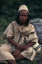 Portrait of Ika mama priest Juan de Jose wearing traditional cactus woven cactus fibre helmet and woven wool&cotton manta cloak and trousers.Fine spun cotton amulets on wrist to protect and ward off e...