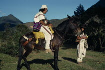 Ika leader Vicente Villafana on mule with another man standing at his side  both in traditional dress of woven wool&cotton mantas cloaks  mochilas shoulder carrying bags. Vicente wears a woven cactus...