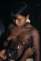 Young Embera daughters with sweet-smelling lilies in their ears  paint their bodies with black dye extracted from the indedible Jagua fruit in preparation for their mothers curing ceremony.Pacific co...