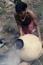 Embera woman uses molten beeswax to seal a  cantaro  water-container/pot to make it completely watertight  after firing the pot at the riverside.Pacific coastal region tribe vessel American Colombian...